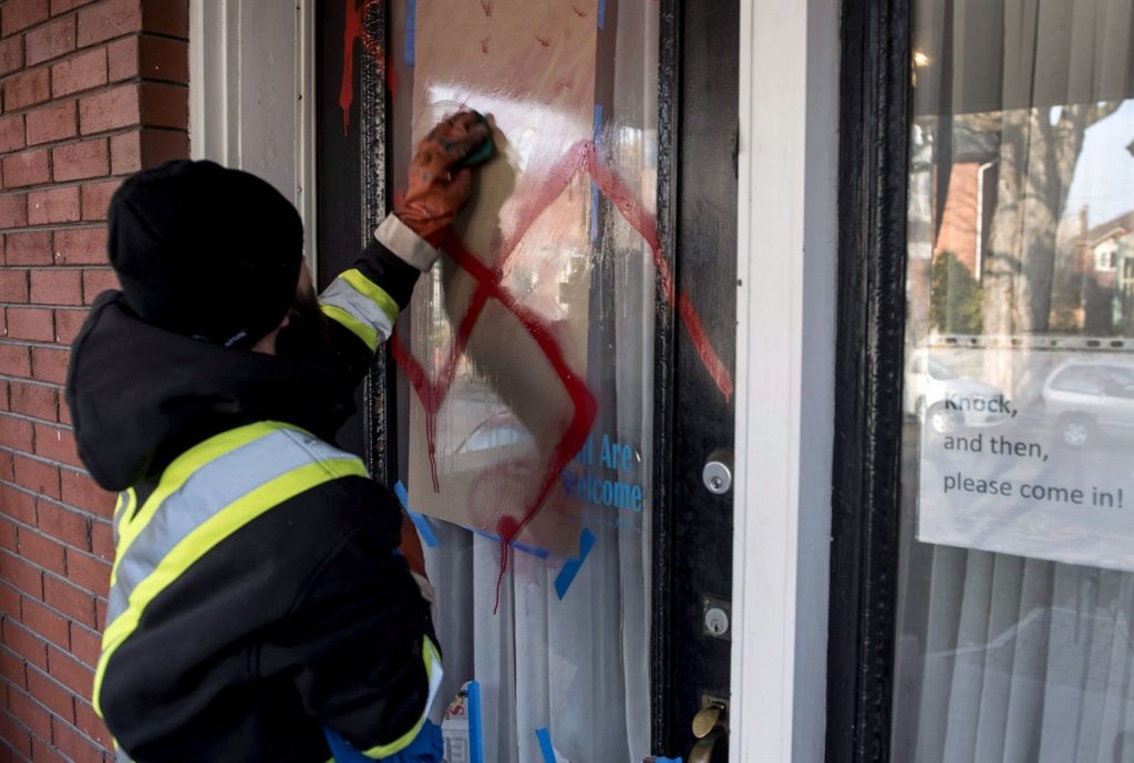 A graffiti removal worker cleans anti-Semitic graffiti