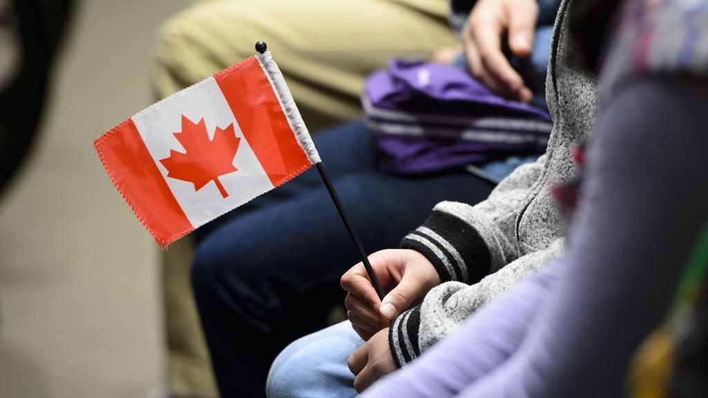 A new Canadian holds a flag as she takes part in a citizenship ceremony on Parliament Hill in Ottawa on April 17, 2019, to mark the 37th anniversary of the Canadian Charter of Rights and Freedoms