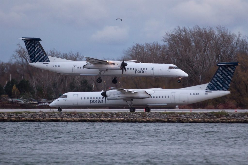 A Porter Airlines plane lands next to a taxiing plane at Toronto's Island Airport