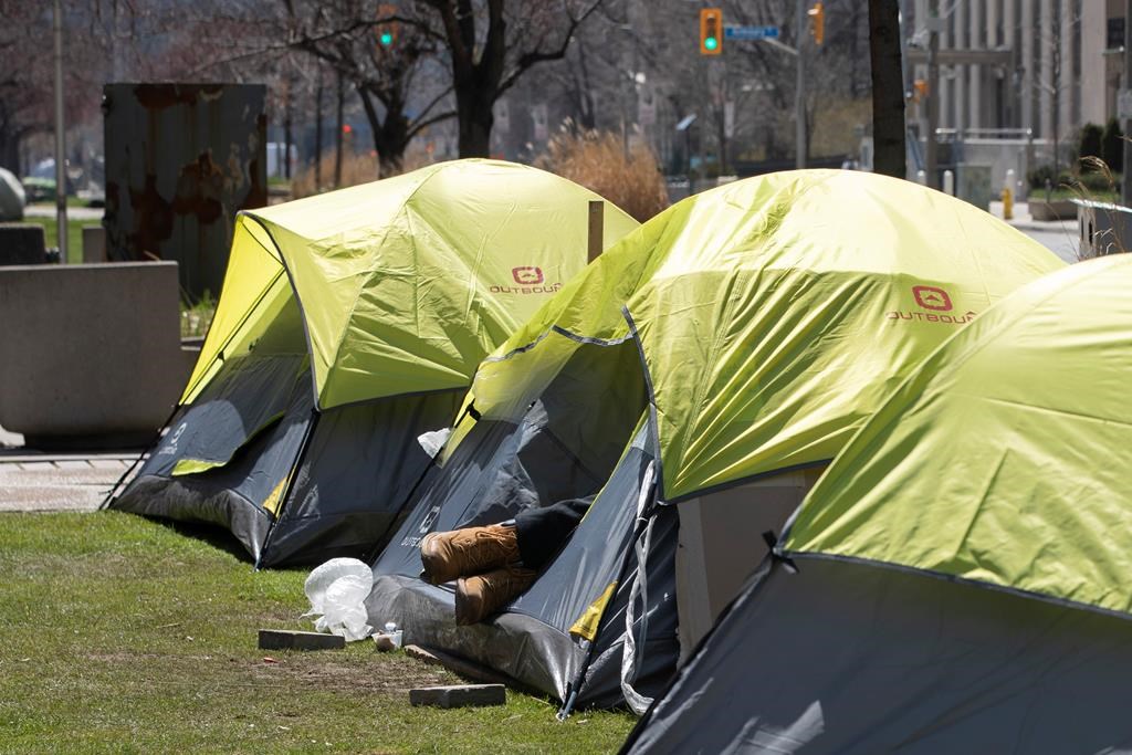 A person expierencing homelessness lies in a tent pitched in a centre reservation in downtown in Toronto on Saturday, April 18 2020.