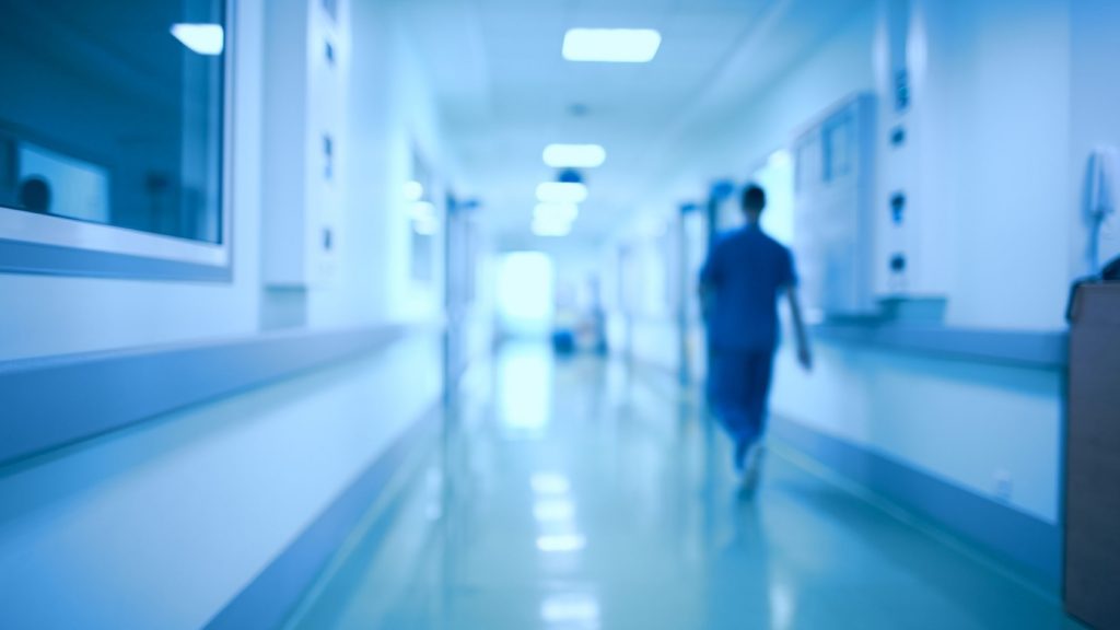 A health care worker walks down a hospital hallway.