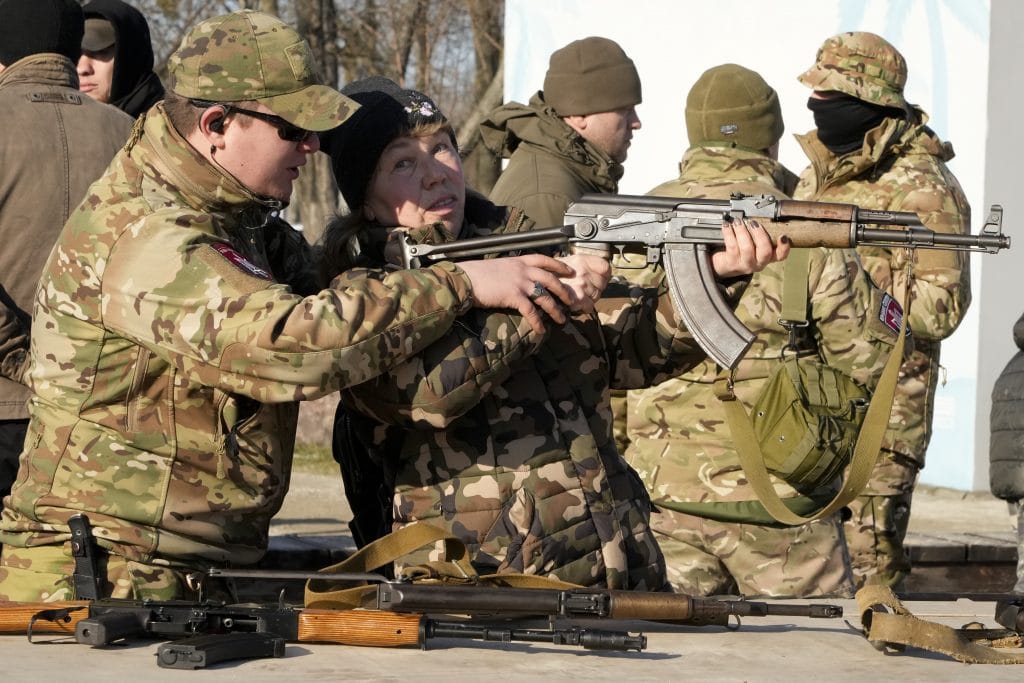 An instructor shows a woman how to use a Kalashnikov assault rifle