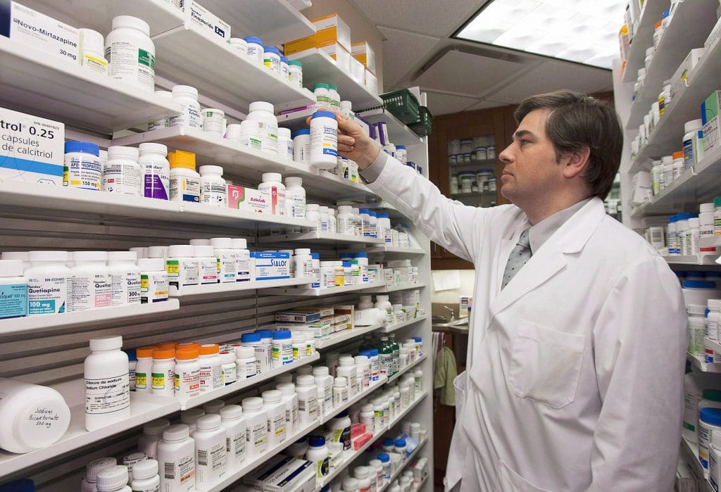 Pharmacist Denis Boissinot checks a bottle on a shelf at his pharmacy