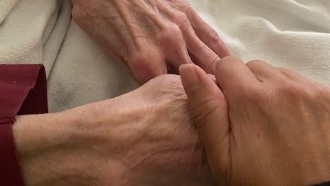 Yvonne Crossman holds her mother's hand during her hospital stay