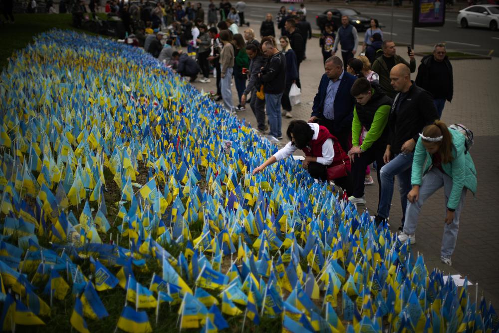 ukrainian flags People place Ukrainian flags in memory of civilians killed