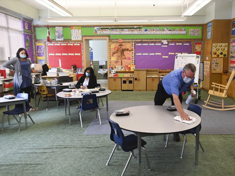 A man sanitizes table surfaces in a kindergarten classroom in Scarborough, Ont., on Monday, September 14, 2020.