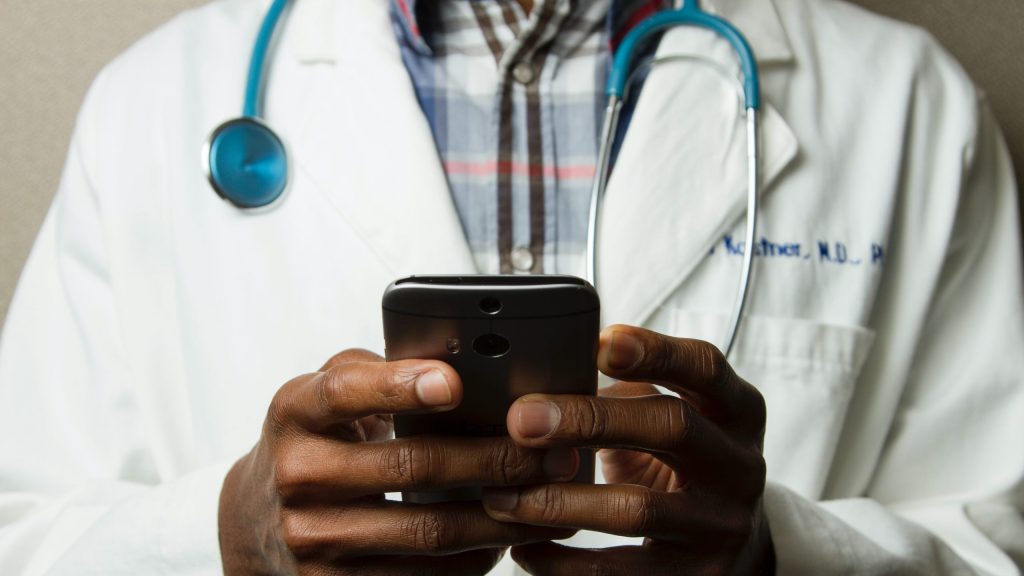 A doctor is seen on his smartphone.
