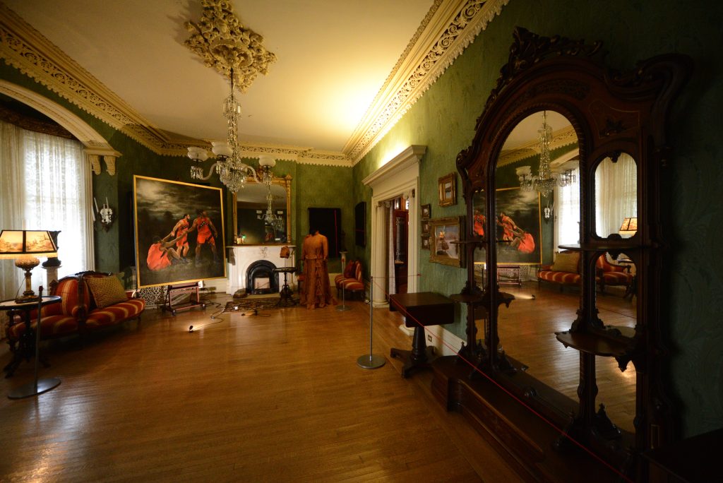 On the main floor of the museum, a large painting of three Toronto Raptors is featured beside a reimagined dress for Mrs. Pipkin.