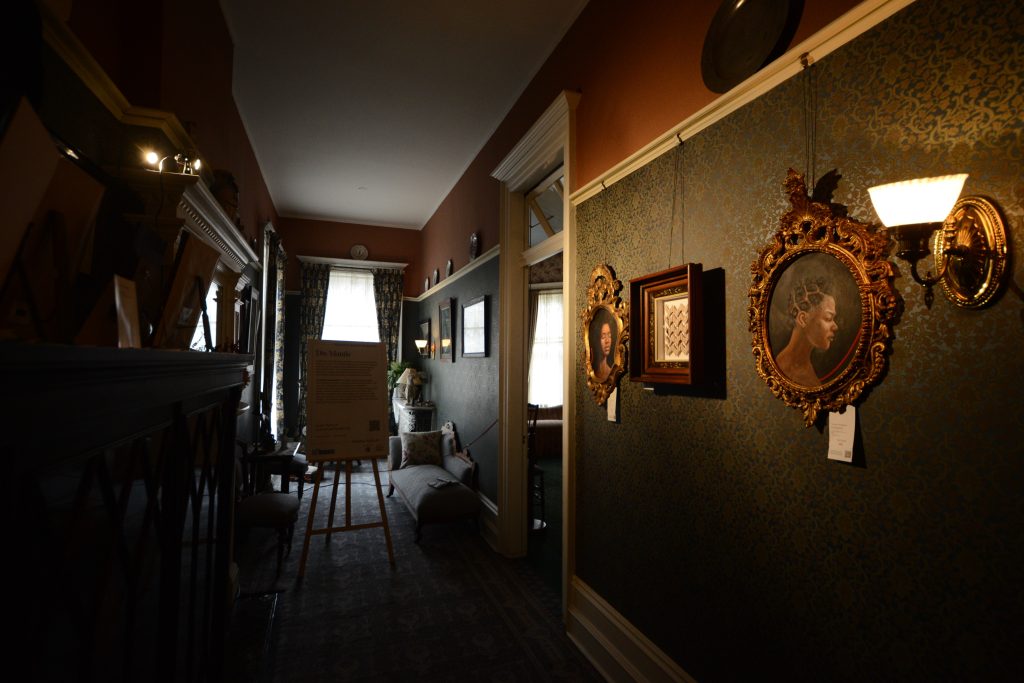 In one hallway of Spadina Museum, commissioned portraits of Black women are highlighted (right) while portraits and photographs of the Austin family are covered or turned away (left).