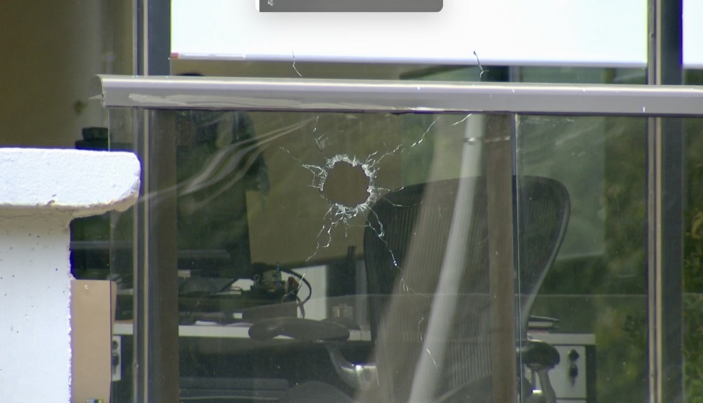 A bullet hole can be seen in the window of the property management's office at an apartment building on Eastmount Avenue