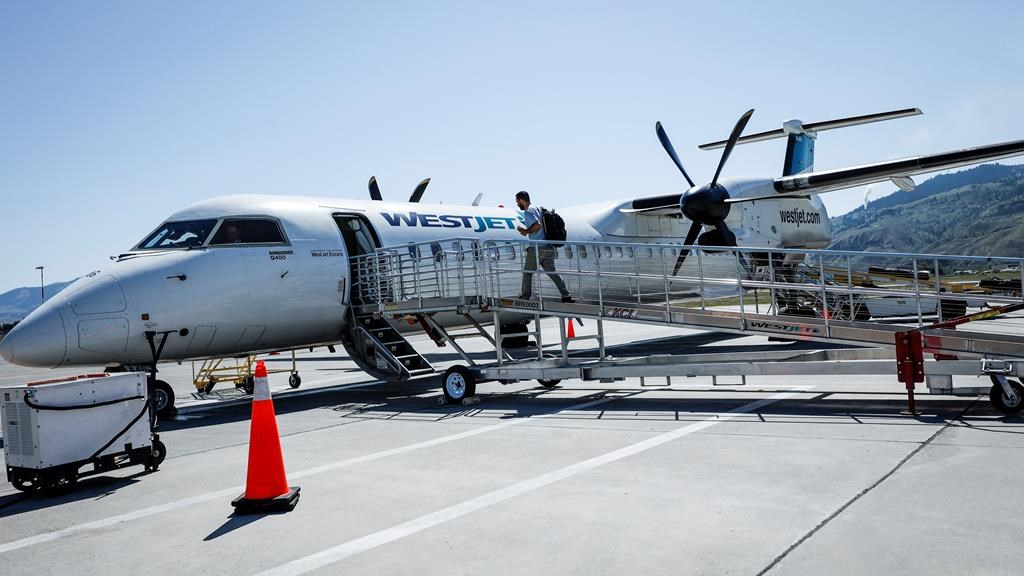 A passenger boards a WestJet Encore Bombardier Q400 twin-engined turboprop aircraft in Kamloops.