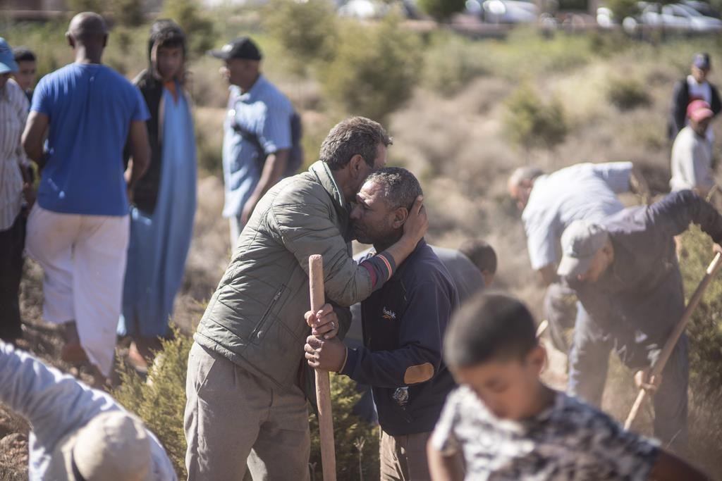 People comfort each other while digging graves for victims of the earthquake in Morocco