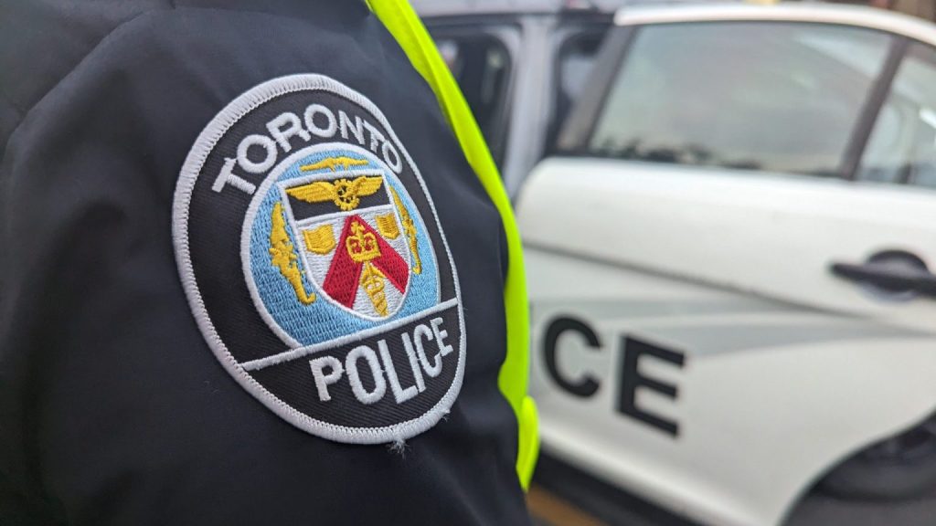 Toronto police badge on officer shoulder with cruiser.