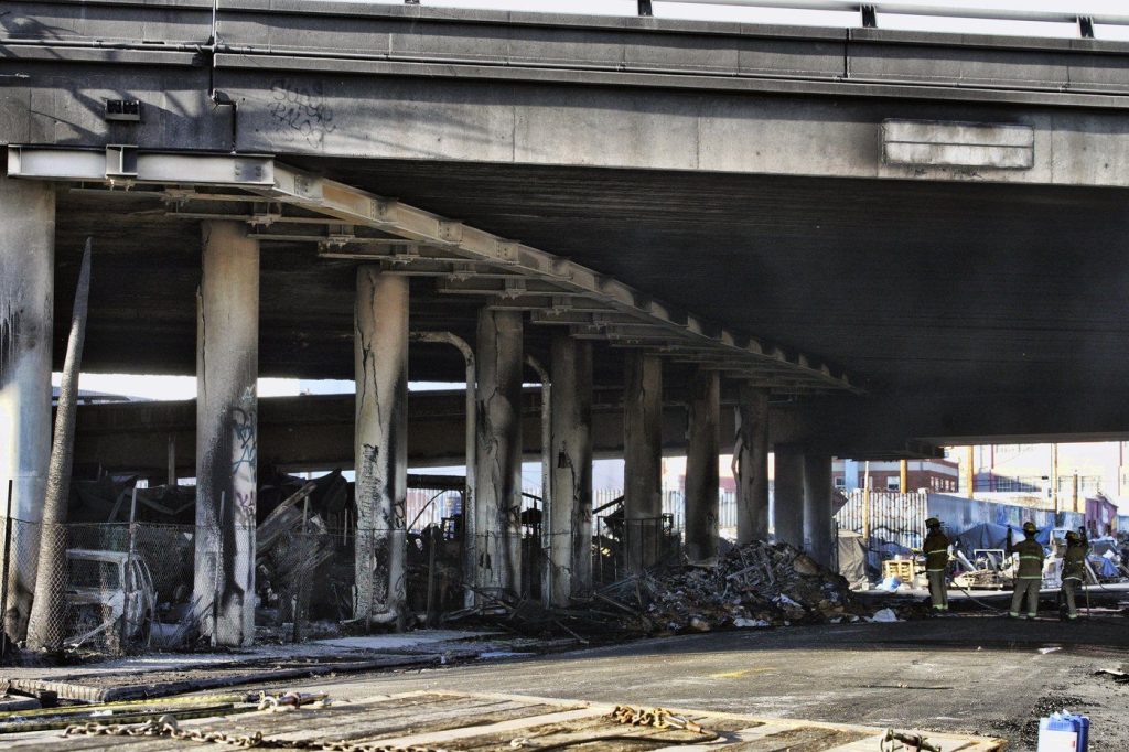 Los Angeles firefighters mop up from a fire under Interstate 10