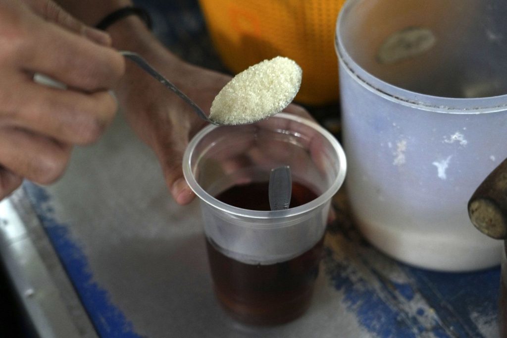 An employee puts a spoon of sugar into a cup of coffee