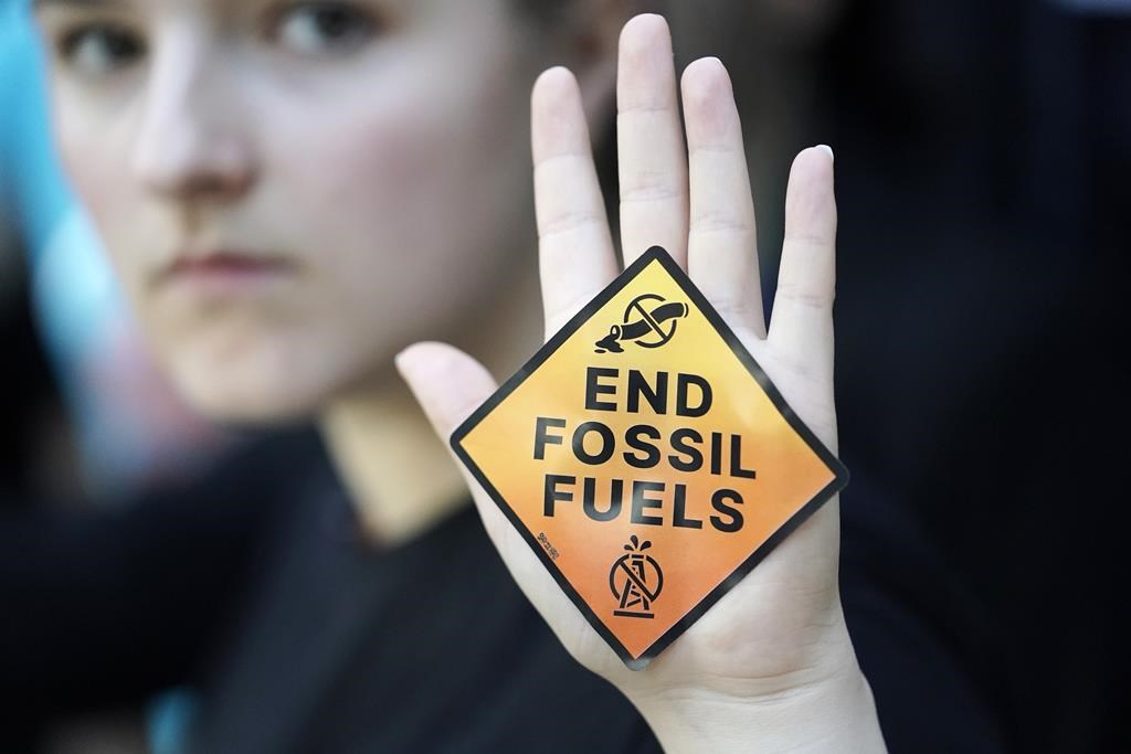 A demonstrator displays a sign reading "end fossil fuels" at the COP28 U.N. Climate Summit