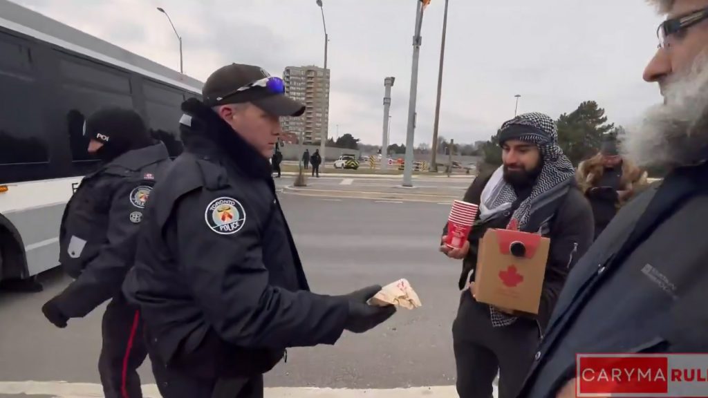 Still taken from video showing Toronto police delivering coffee and donuts to a demonstrator on the Avenue Road Bridge.