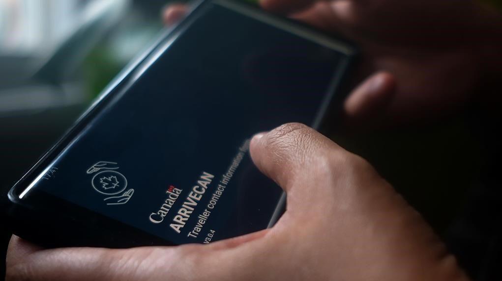 A person holds a smartphone set to the opening screen of the ArriveCan app on June 29, 2022