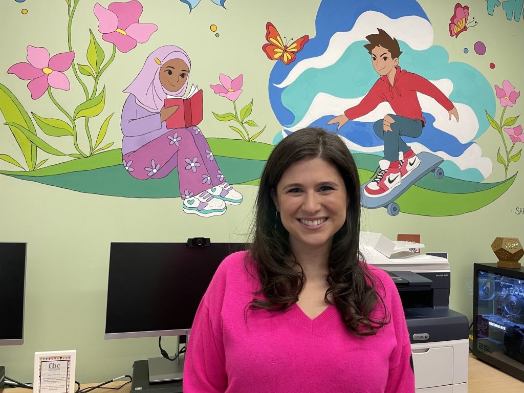 Shira Taylor, creator and director of Sex Education by Theatre stands in front of a mural in Flemingdon Health Centre. 