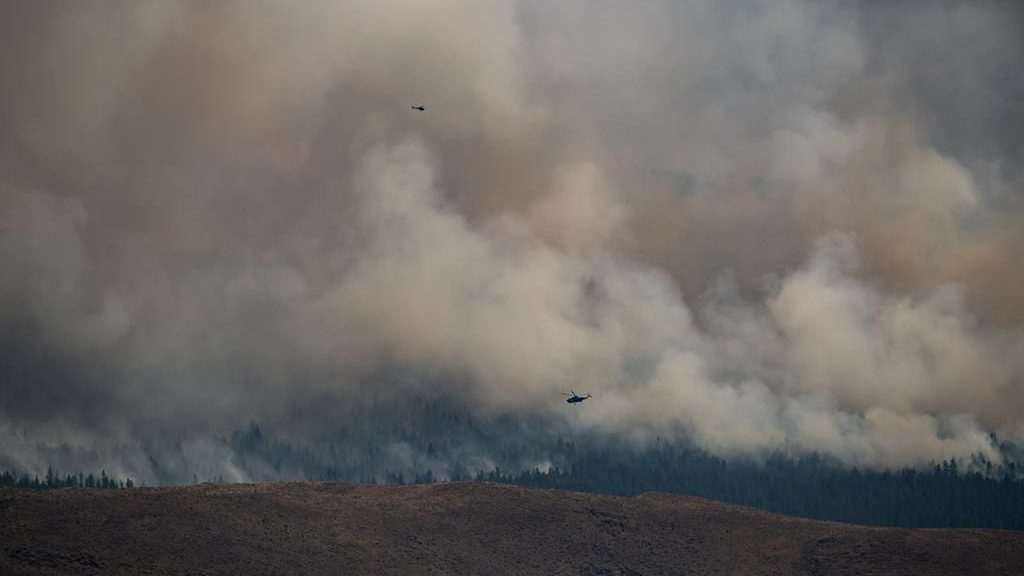 Helicopters fly past the Tremont Creek wildfire as it burns on the mountains above Ashcroft, B.C., on July 16, 2021