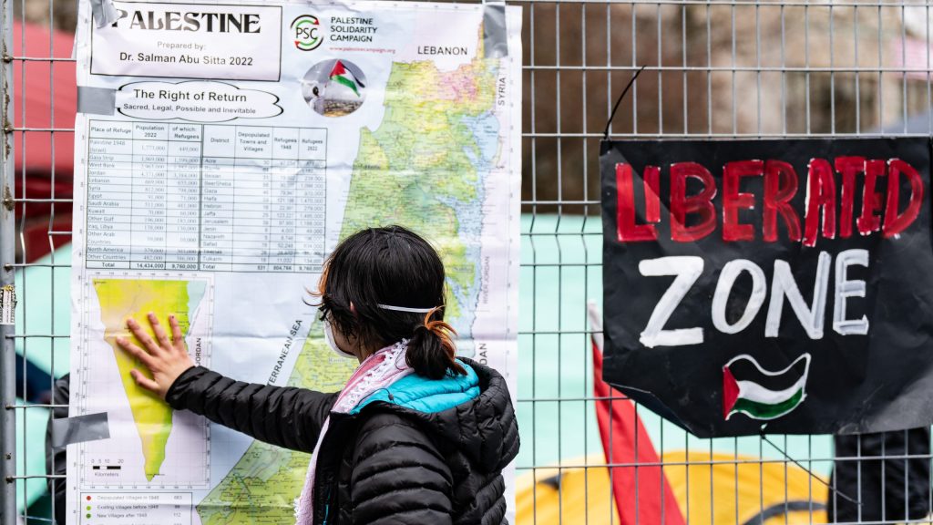 A pro-Palestinian activist looks at a map of Palestine taped to the fencing around their encampment on McGill University's campus in Montreal, Monday, April 29, 2024.