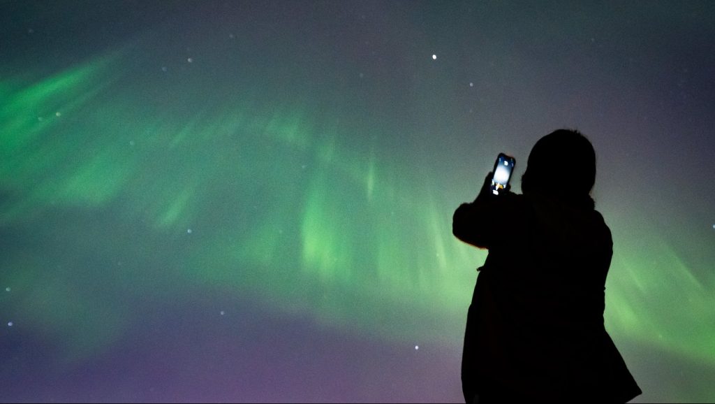 A person takes a photo of the northern lights in Vancouver on May 11, 2024