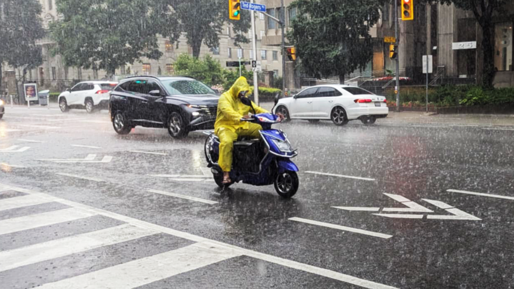 Person driving motorcycle in rain in Toronto