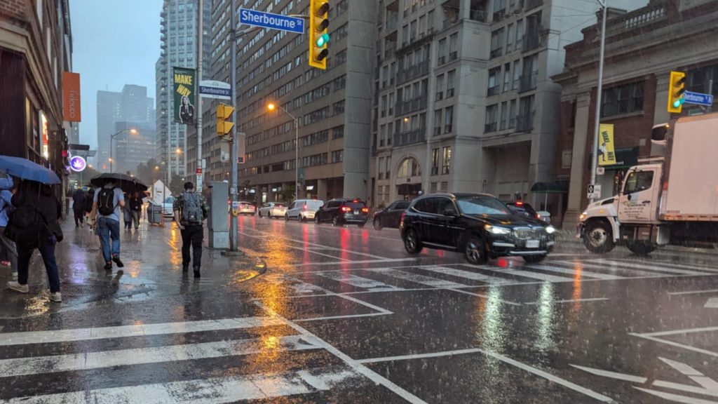 Pedestrians walk in the rain at Bloor Street East and Sherbourne Street in Toronto on July 16, 2024