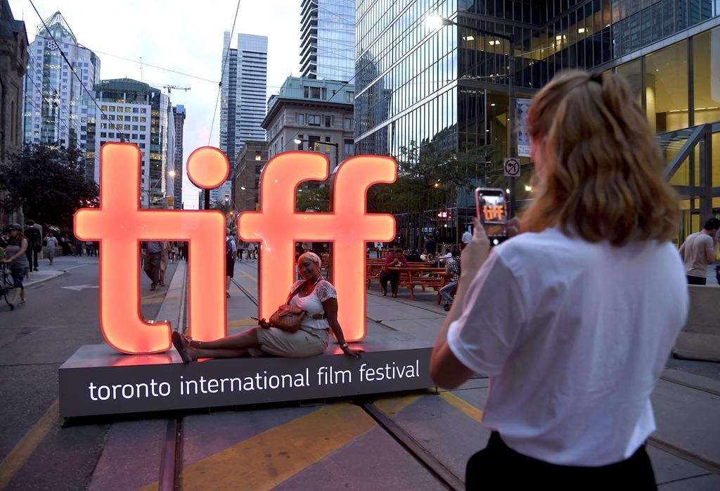 A volunteer takes a photo in front of a festival sign on Day 1 of the Toronto International Film Festival on Sept. 6, 2018.