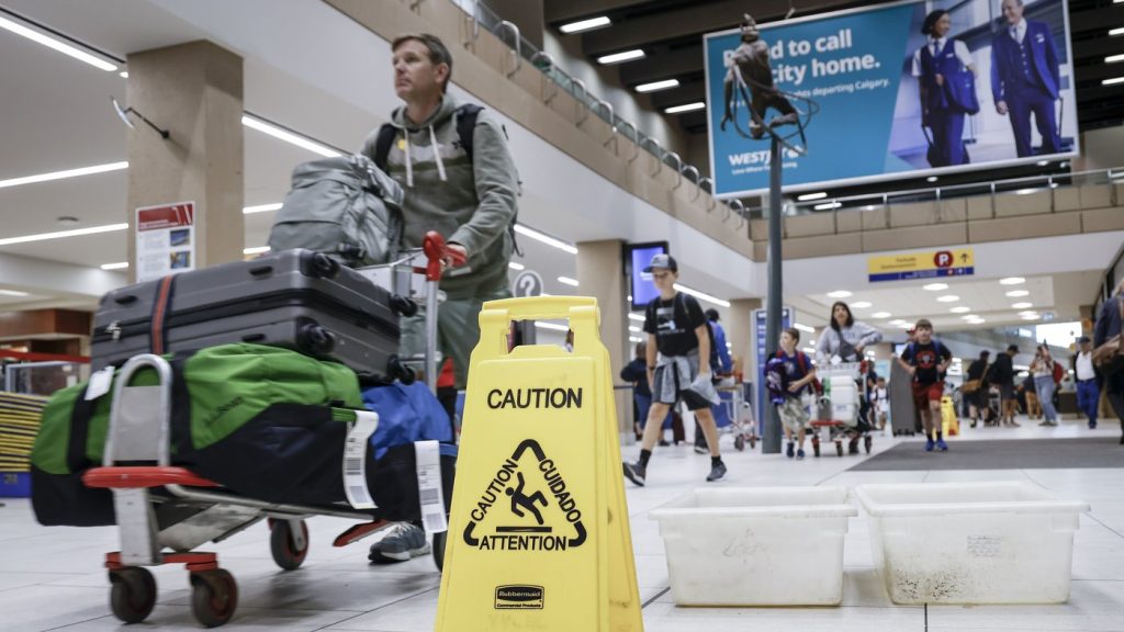 Travellers manoeuvre around buckets catching leaks at Calgary International Airport after parts of its domestic terminal building were damaged due to hail and heavy rainfall in Calgary on Aug. 6, 2024