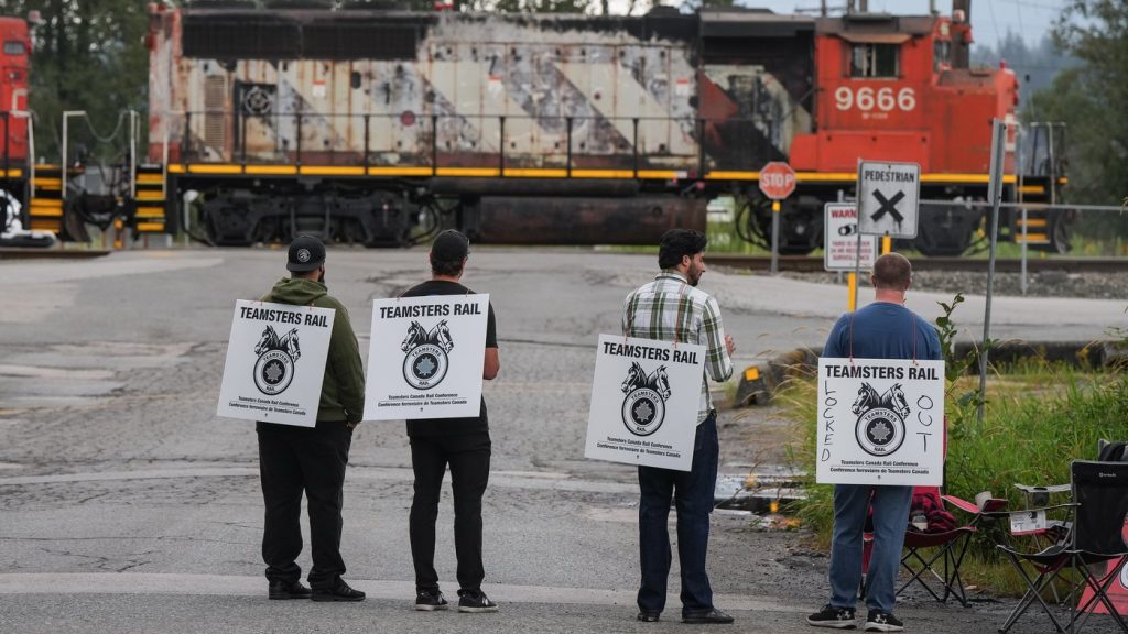 Locked-out Canadian National Railway workers stand at a picket line as locomotives are moved by management at CN Rail's Thornton Yard, in Surrey, B.C., on Aug. 22, 2024