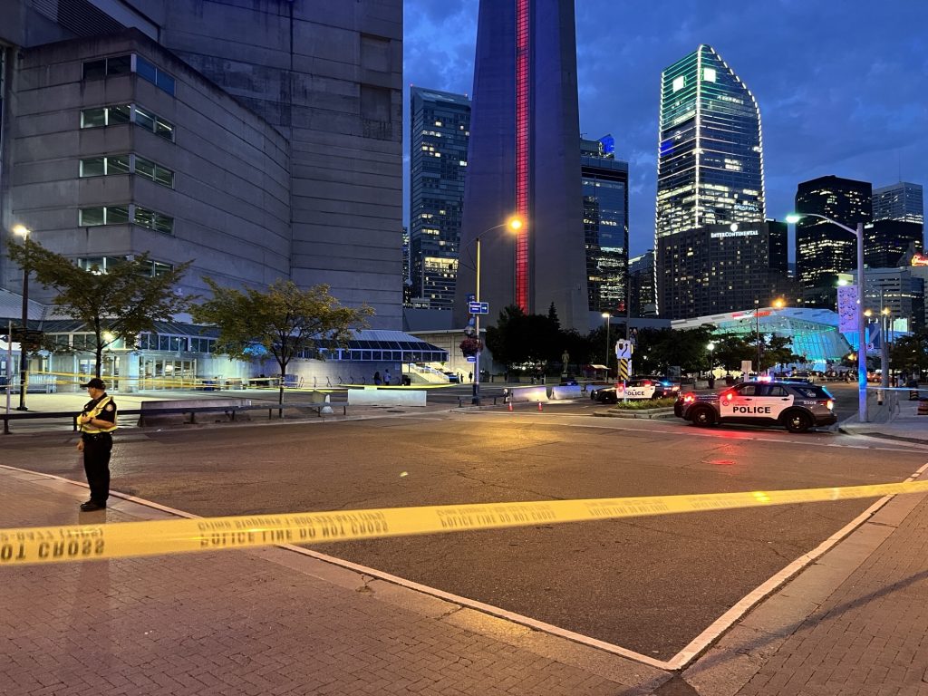 Toronto police officers block off the intersection of Rees Street and Bremner Boulevard Saturday evening. Investigators say an officer was struck and injured by a motorcycle.