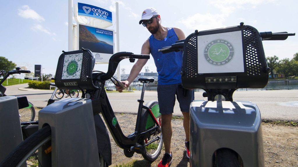 A man scans a code to pick up a shared bike at a docking station in Toronto on Sept. 2, 2020