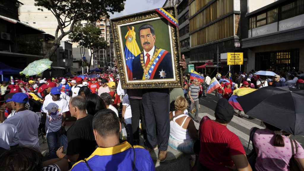 A supporter holds a framed image of President Nicolas Maduro as people gather for a government rally in Caracas, Venezuela, on Aug. 3, 2024