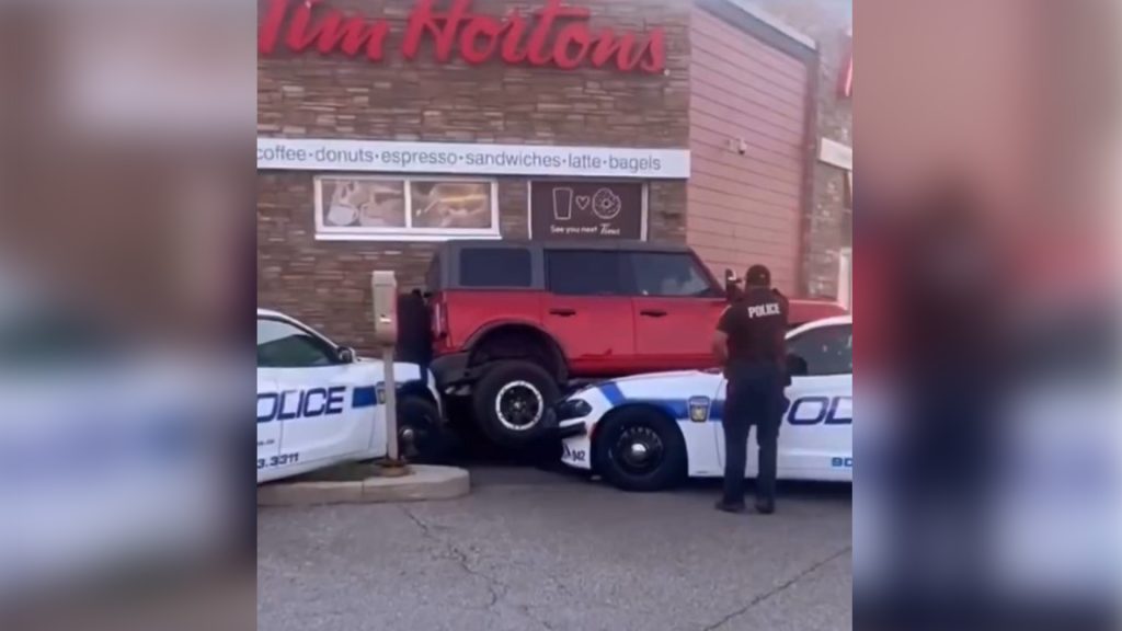 Officers are seen attempting to prevent a driver from fleeing