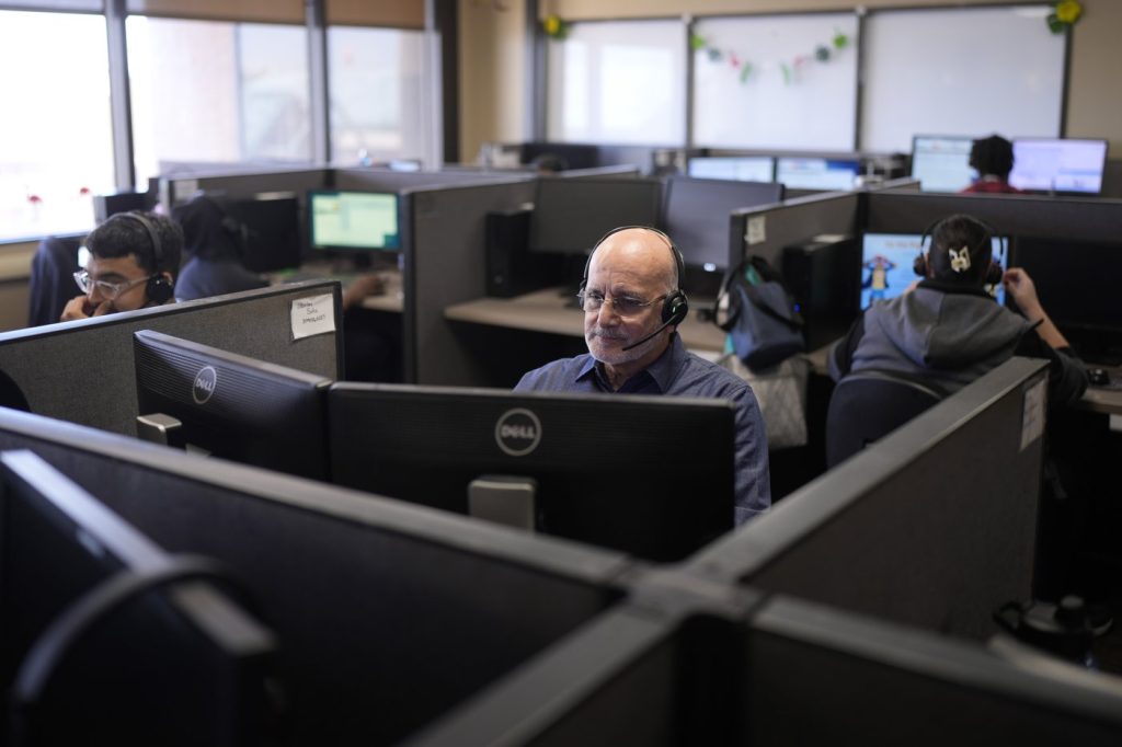 Customer Experience Representatives Stanley Solis, center, and other representatives take calls at an Alorica center, Monday, Aug. 19, 2024, in San Antonio