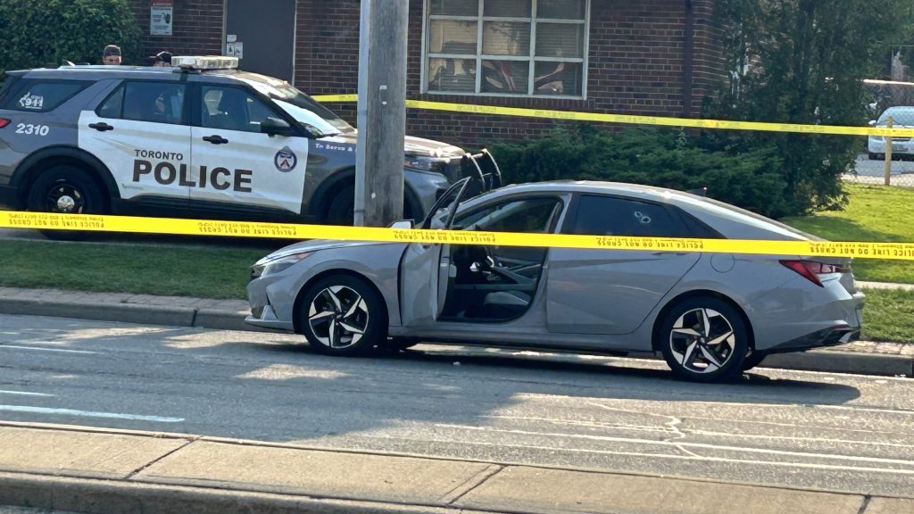 A silver sedan shows signs of gunfire with at least four bullet holes visible