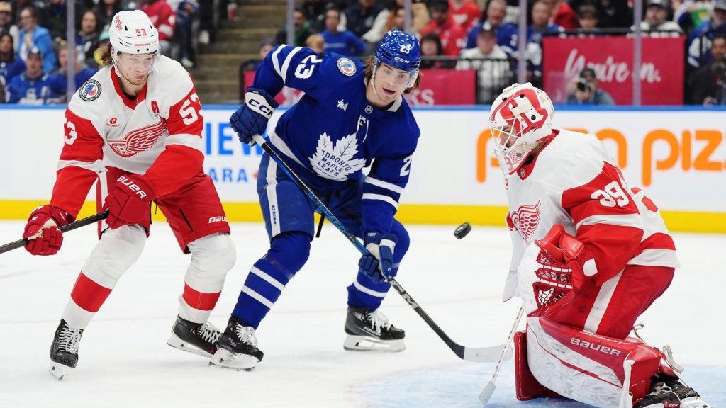 Detroit Red Wings' goaltender Cam Talbot (39) makes a save as Moritz Seider (53) and Toronto Maple Leafs' Matthew Knies (23) look on