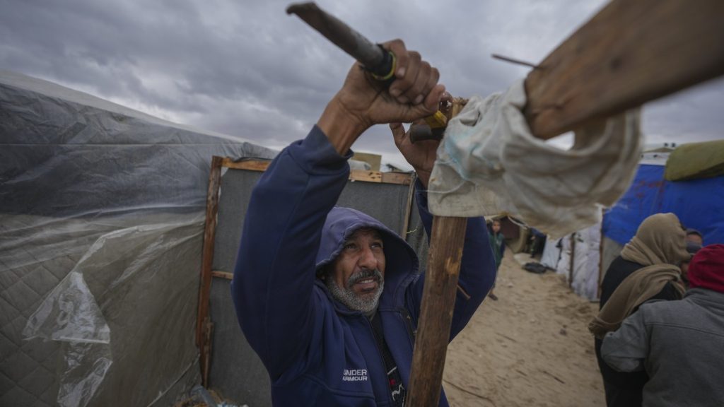 A Palestinian secures his tent as storm clouds loom over a camp for displaced Palestinians on the beach front in Deir al-Balah, Gaza Strip, on Nov. 26, 2024