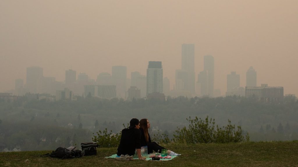 Smoke from wildfires blankets the city as a couple has a picnic in Edmonton, Saturday, May 11, 2024. THE CANADIAN PRESS/Jason Franson 