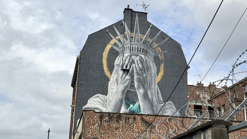 A mural by Dutch artist Judith de Leeuw shows the Statue of Liberty covering her eyes with her hands, in Roubaix, northern France, on July 14, 2025. (AP Photo/Sylvain Plazy) 