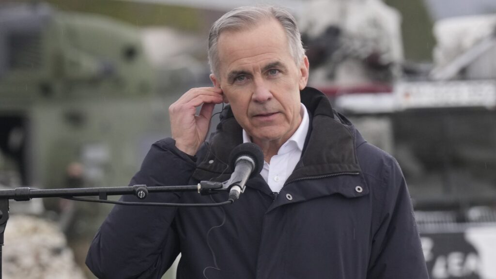 Prime Minister Mark Carney adjusts a translation aid as he participates in a joint news conference with German Chancellor Friedrich Merz and Norwegian Prime Minister Jonas Gahr Store following a tour of the site of NATO Exercise Cold Response in Bardufoss, Norway, Friday, March 13, 2026. THE CANADIAN PRESS/Adrian Wyld