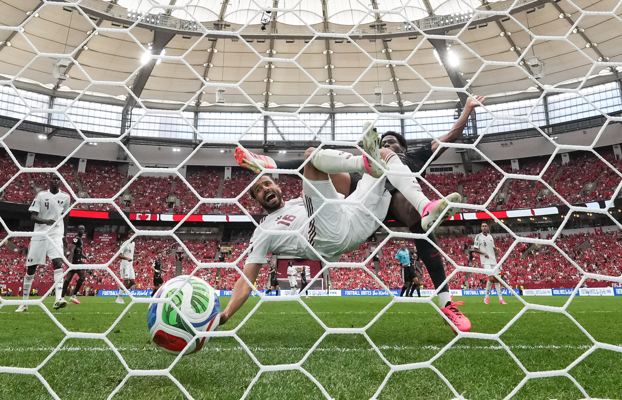 Jonathan David, back right, scores past Qatar defender Boualem Houkhi (16) during the first half of the group-stage World Cup B match in Vancouver on Thursday, June 18, 2026. THE CANADIAN PRESS/Darryl Dyck